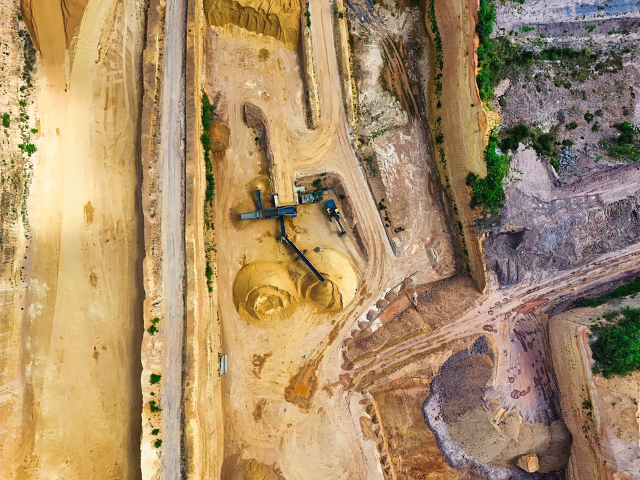 Aerial view of a large open-pit mine with terraced excavation during summer.