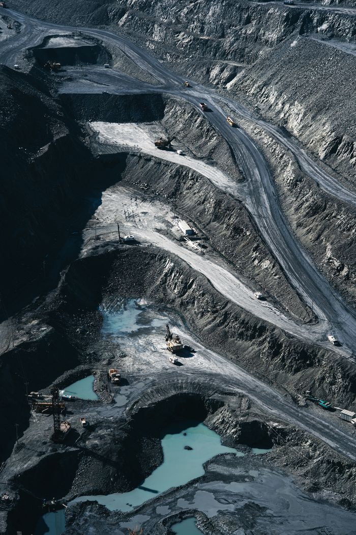 Aerial shot of an expansive open-pit mining operation with industrial machinery and mining layers visible.